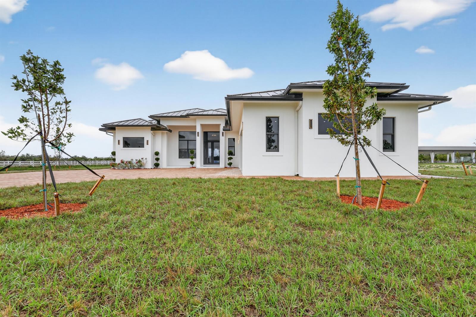 A modern white single-story house with a dark metal roof sits on a grassy lot — 3644 Frog Holw, Loxahatchee FL 33470, LOXAHATCHEE, FL