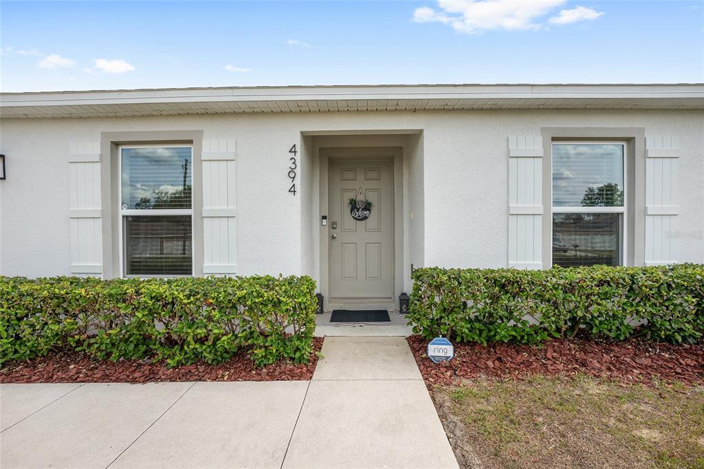 The exterior of a single-story house features a beige front door, white shutters, and hedges — 4394 SW 170TH STREET ROAD, OCALA, FL