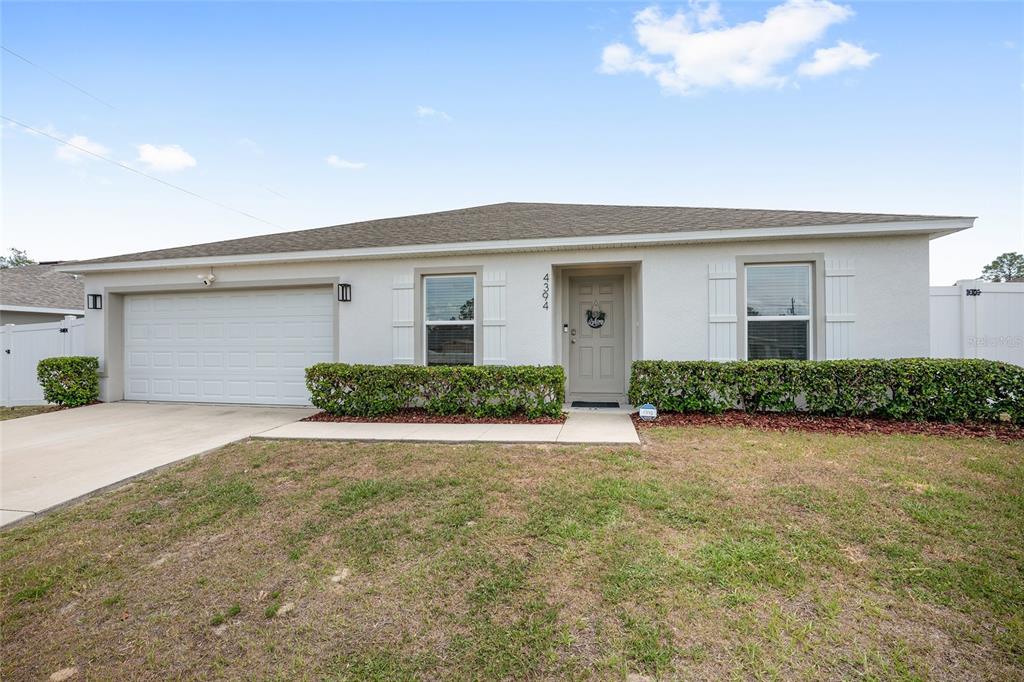 A single-story house with a white exterior, a two-car garage, and a front lawn — 4394 SW 170TH STREET ROAD, OCALA, FL