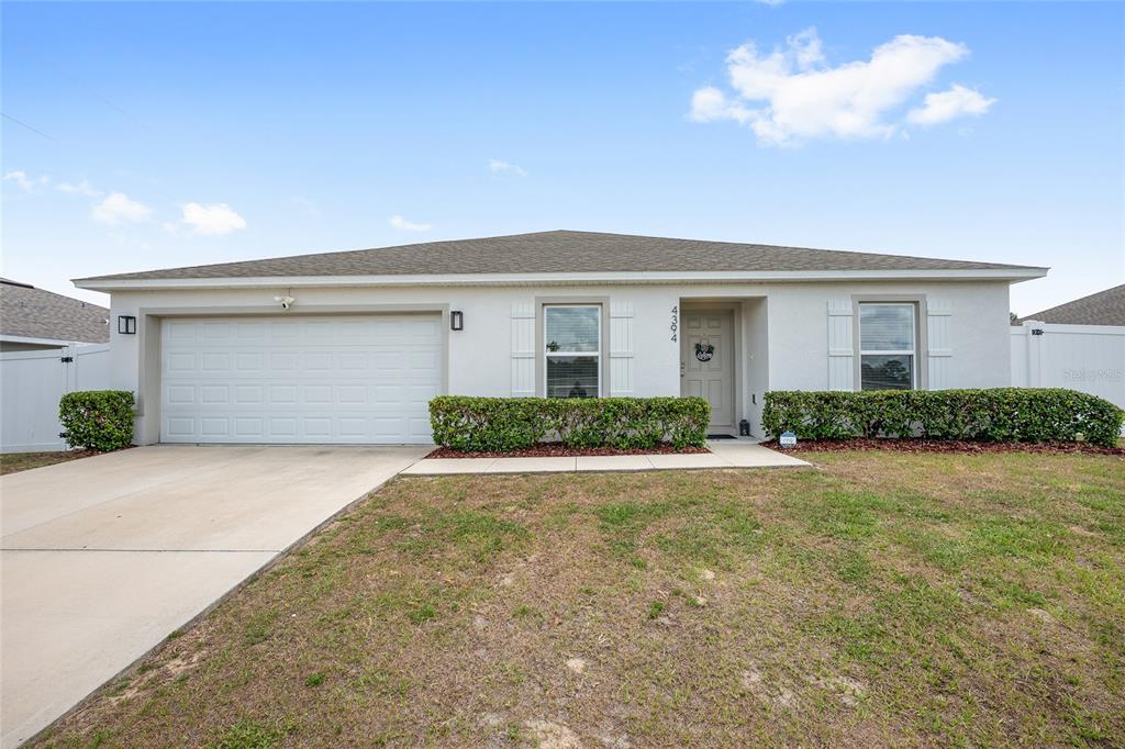 A single-story house with a white stucco exterior, a two-car garage, and a front lawn — 4394 SW 170TH STREET ROAD, OCALA, FL