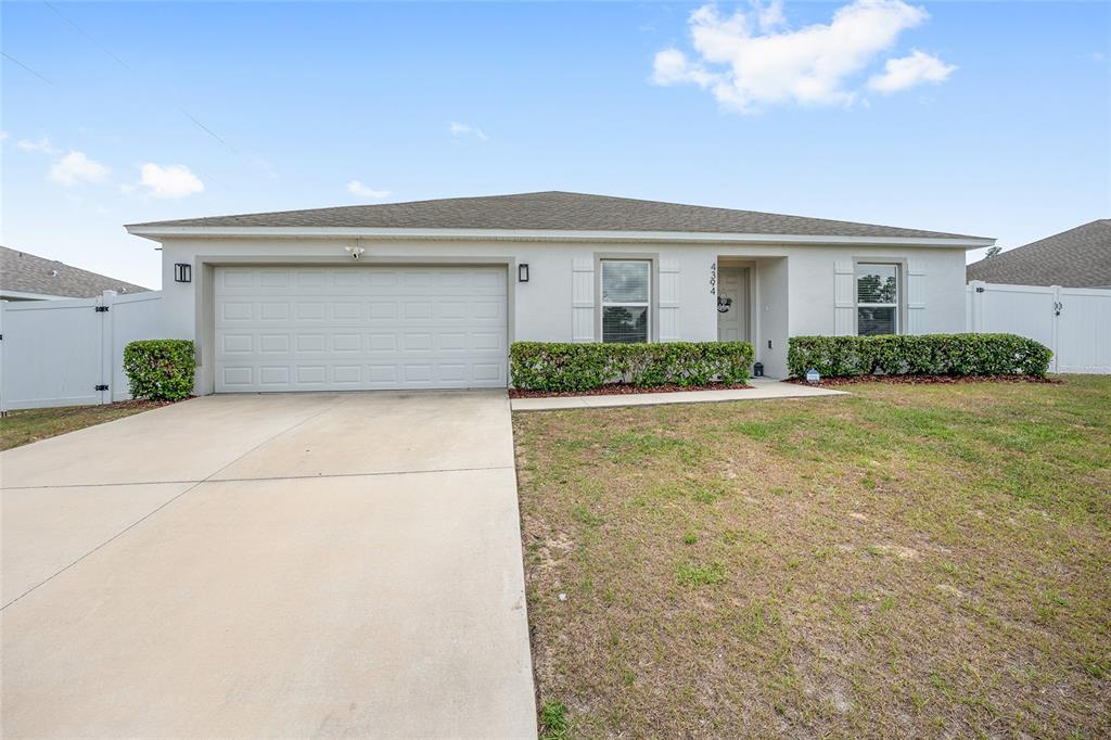 A single-story house with a white stucco exterior, a two-car garage, and a front lawn — 4394 SW 170TH STREET ROAD, OCALA, FL
