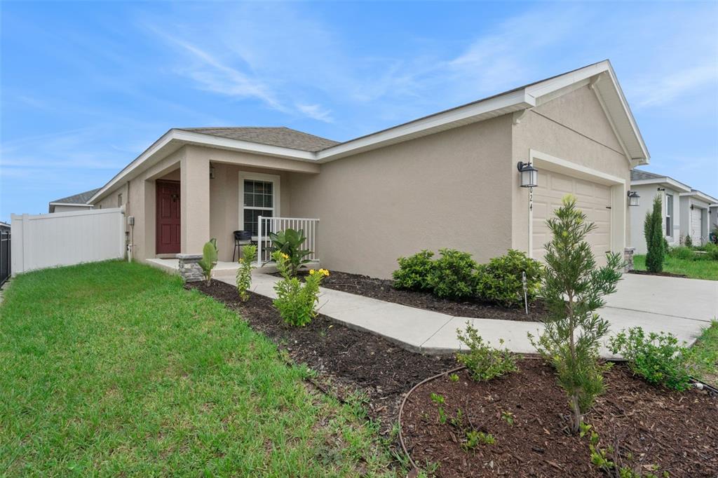 A single-story house with a beige stucco exterior, a red front door, and a garage — 2024 NOBLE DRIVE, DAVENPORT, FL