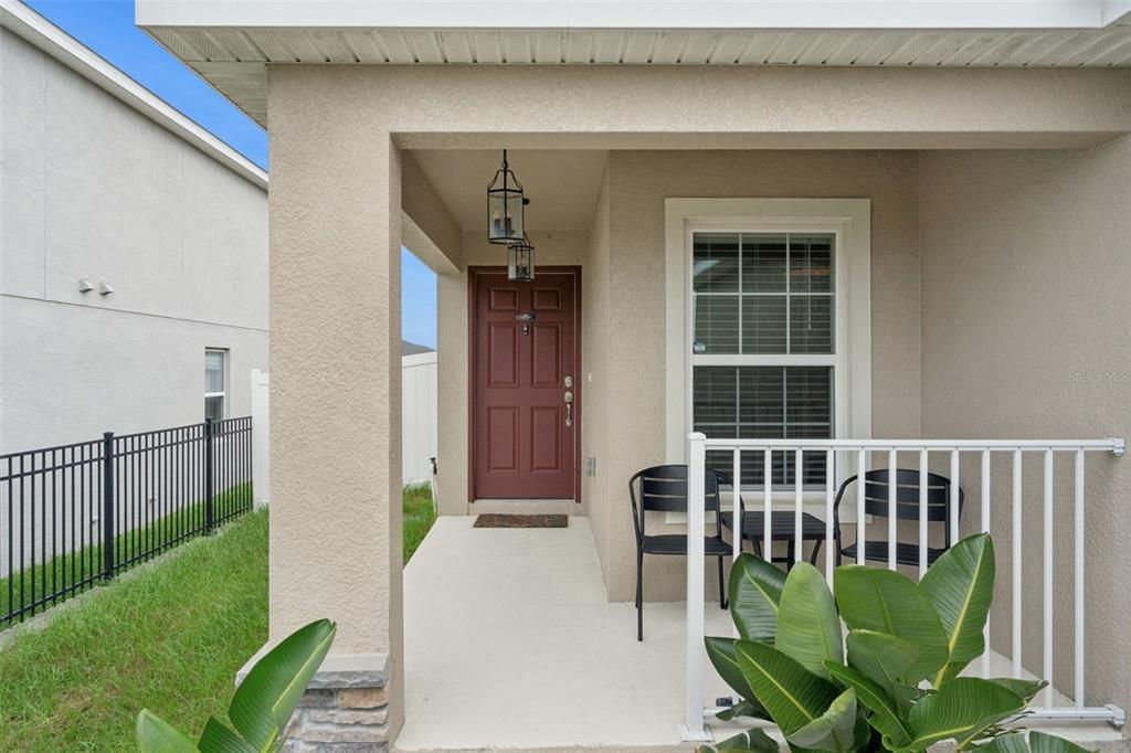 A covered front porch with a red door, two chairs, and a small table — 2024 NOBLE DRIVE, DAVENPORT, FL
