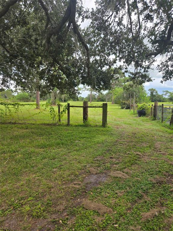 A grassy field is enclosed by a wire fence with wooden posts under large trees — 885 LAKE MARIAN ROAD, KENANSVILLE, FL
