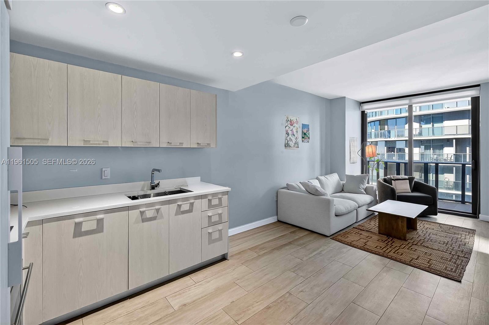 A studio apartment features light wood cabinets, a kitchenette, a sofa, and a balcony view — 45 SW 9th St # 3807, Miami FL 33130, MIAMI, FL