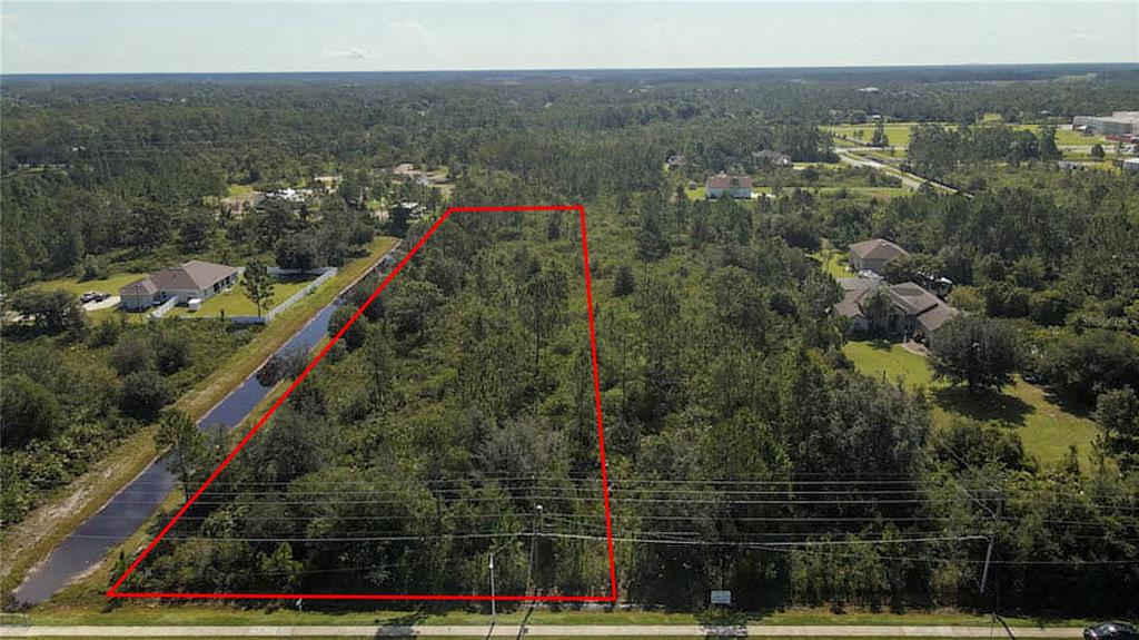 An aerial view shows a rectangular, wooded vacant lot outlined in red next to a canal — 3603 BANCROFT BOULEVARD, ORLANDO, FL