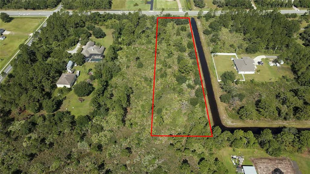 An aerial view shows a rectangular, wooded vacant lot outlined in red next to a canal — 3603 BANCROFT BOULEVARD, ORLANDO, FL