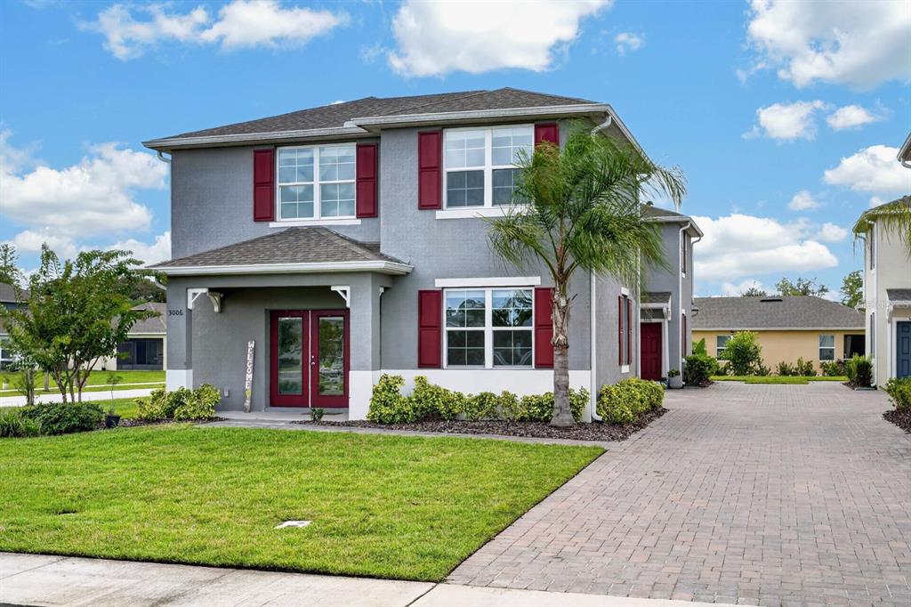 A two-story gray house features red shutters, a brick driveway, and a small palm tree — 3006 MELETO BOULEVARD, NEW SMYRNA BEACH, FL