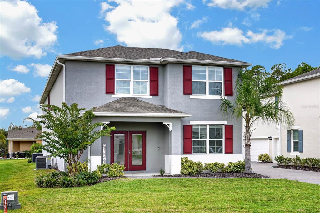 A two-story gray house with red shutters and a front porch under a blue sky — 3006 MELETO BOULEVARD, NEW SMYRNA BEACH, FL