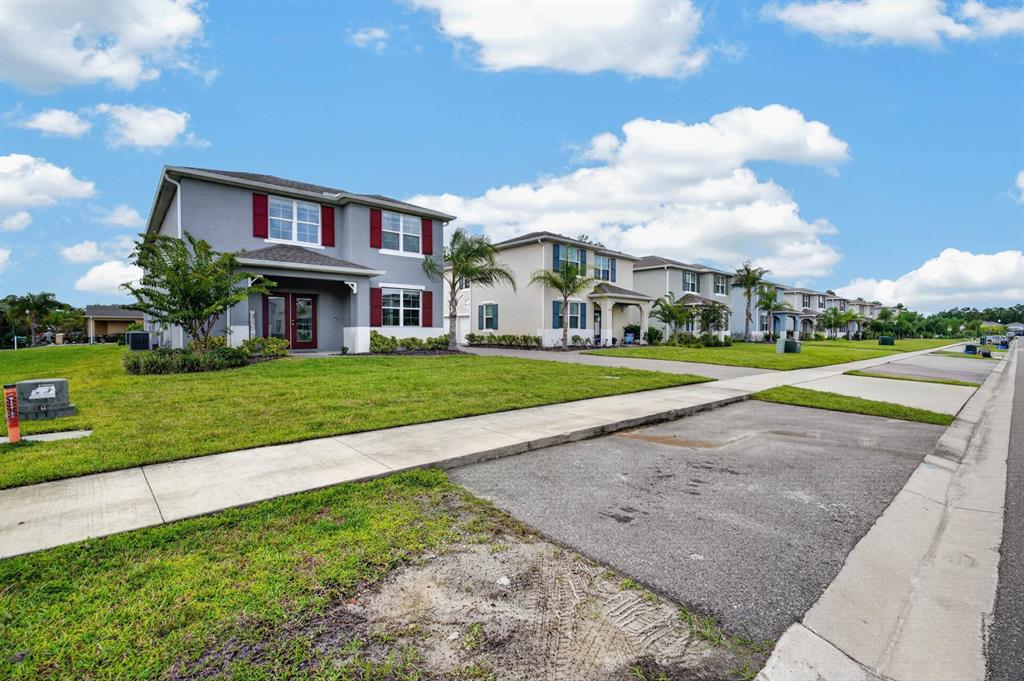 A row of two-story suburban houses with lawns and sidewalks under a blue sky — 3006 MELETO BOULEVARD, NEW SMYRNA BEACH, FL