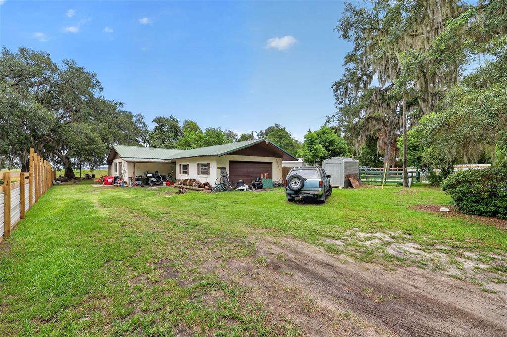 A single-story house with a green metal roof, attached garage, and a large grassy yard — 25155 NE 133RD LANE, SALT SPRINGS, FL