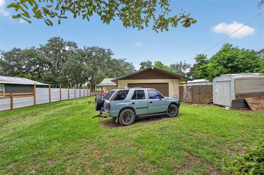 A light blue SUV is parked on a grassy backyard lawn in front of a garage — 25155 NE 133RD LANE, SALT SPRINGS, FL