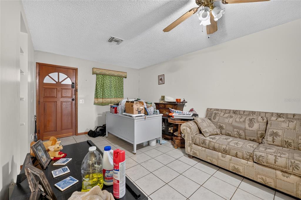 A living room with a tile floor, a patterned sofa, and a ceiling fan — 25155 NE 133RD LANE, SALT SPRINGS, FL