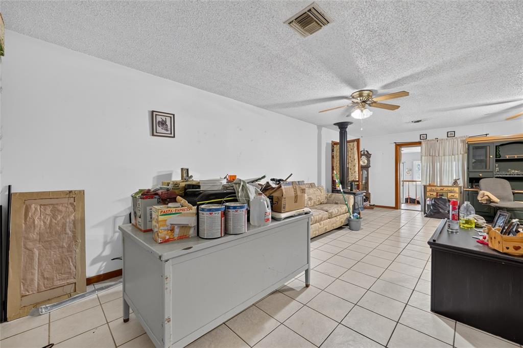 A living room with tiled floors, a ceiling fan, and a large gray storage unit — 25155 NE 133RD LANE, SALT SPRINGS, FL