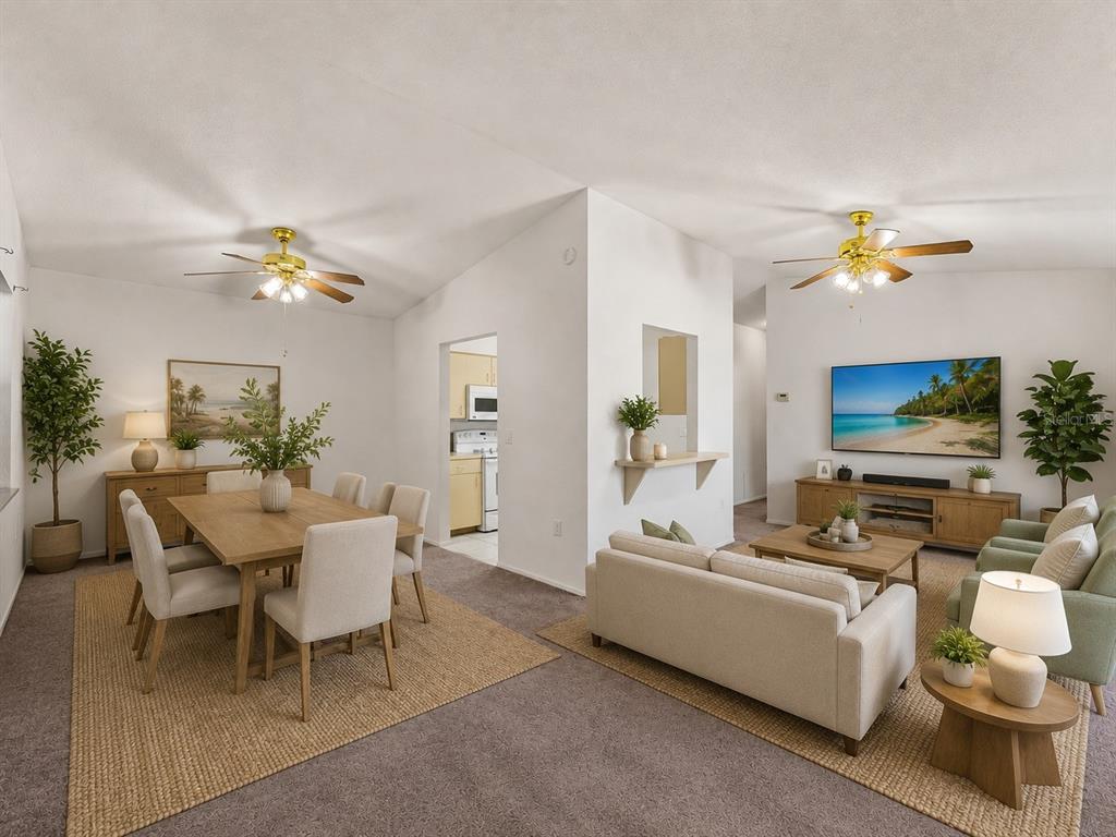 An open-concept living and dining area features neutral furniture, two ceiling fans, and carpeted floors — 22441 WESTCHESTER BOULEVARD UNIT 1500F, PUNTA GORDA, FL