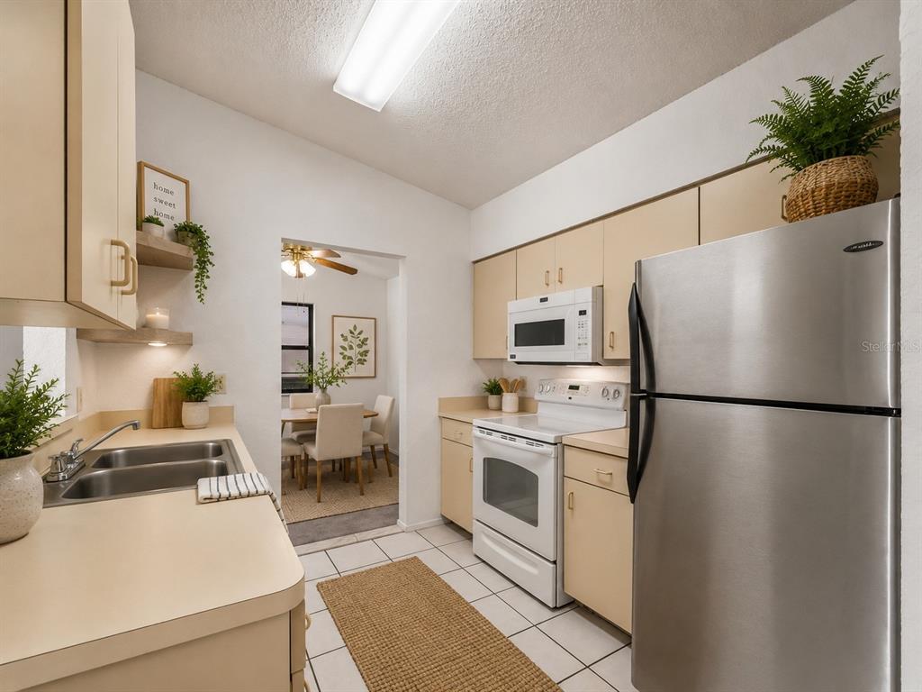 A kitchen with light-colored cabinets, stainless steel appliances, and tile flooring — 22441 WESTCHESTER BOULEVARD UNIT 1500F, PUNTA GORDA, FL