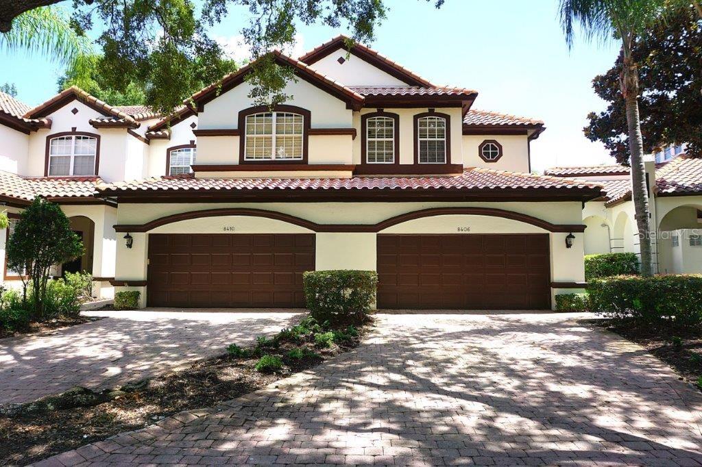 A two-story residential building features a shared driveway and two side-by-side garage doors — 8406 FRESCADA COURT, ORLANDO, FL