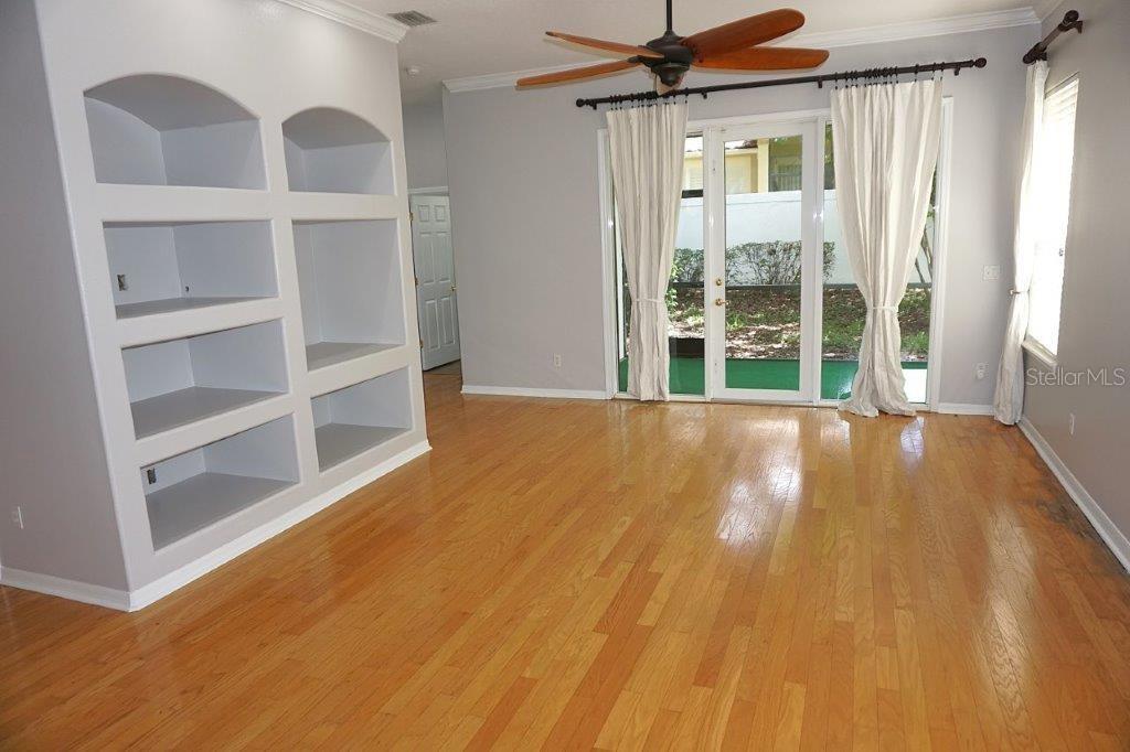 A living room features hardwood floors, a built-in shelving unit, and glass sliding doors — 8406 FRESCADA COURT, ORLANDO, FL
