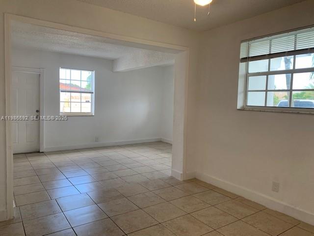 An interior view shows a tiled room with white walls, a doorway, and two windows — 4930 NW 13th St, Lauderhill FL 33313, LAUDERHILL, FL