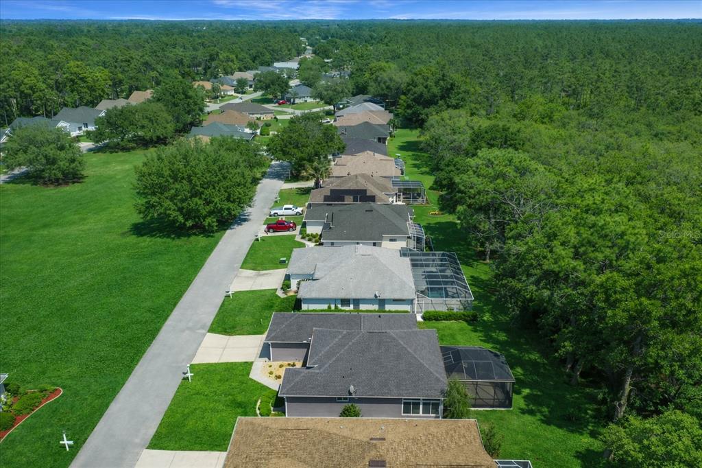 An aerial view shows a suburban street lined with houses, driveways, and surrounding wooded areas — 6790 SW 117TH STREET, OCALA, FL
