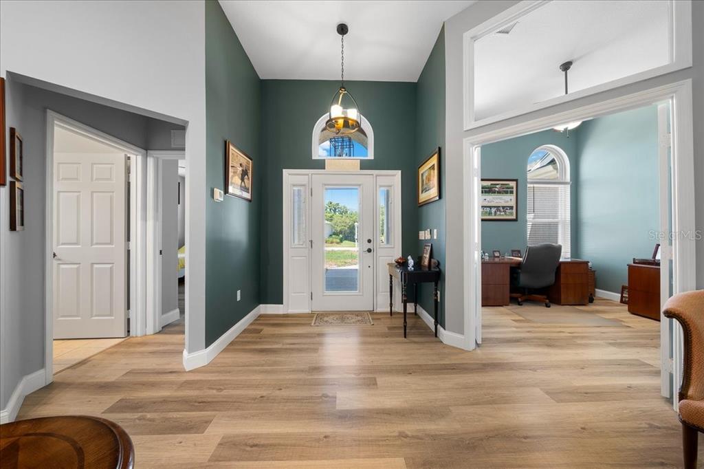 A foyer with dark teal walls, wood-look flooring, and a glass-paneled front door — 6790 SW 117TH STREET, OCALA, FL