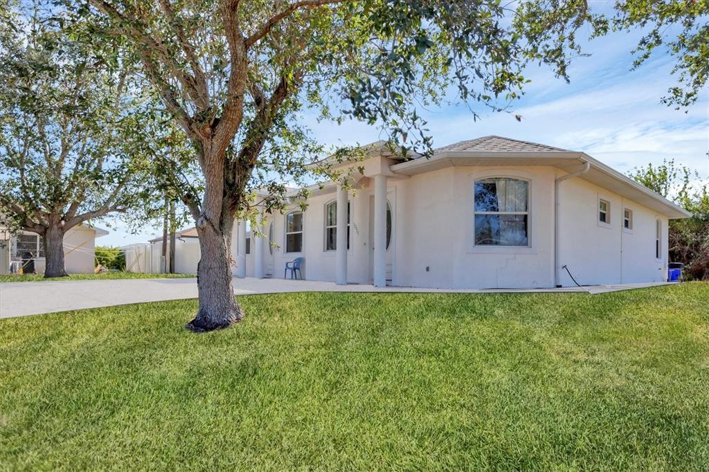 A single-story stucco house with a large tree in the front yard — 12113 CAPILLA LANE, NORTH PORT, FL