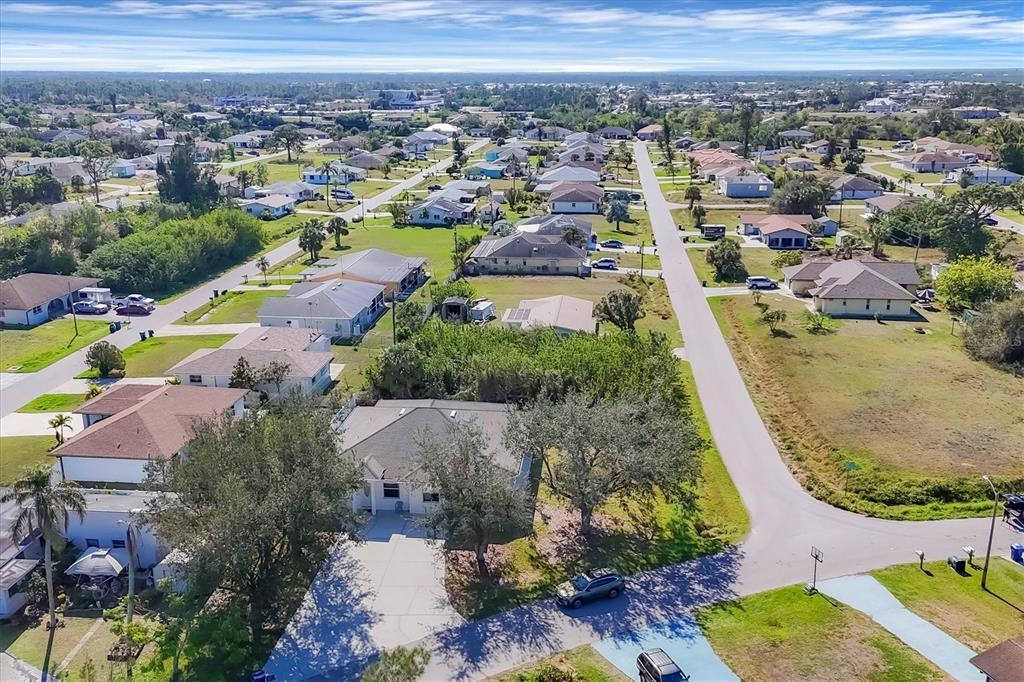 An aerial view shows a suburban neighborhood with single-family homes, paved streets, and green lawns — 12113 CAPILLA LANE, NORTH PORT, FL