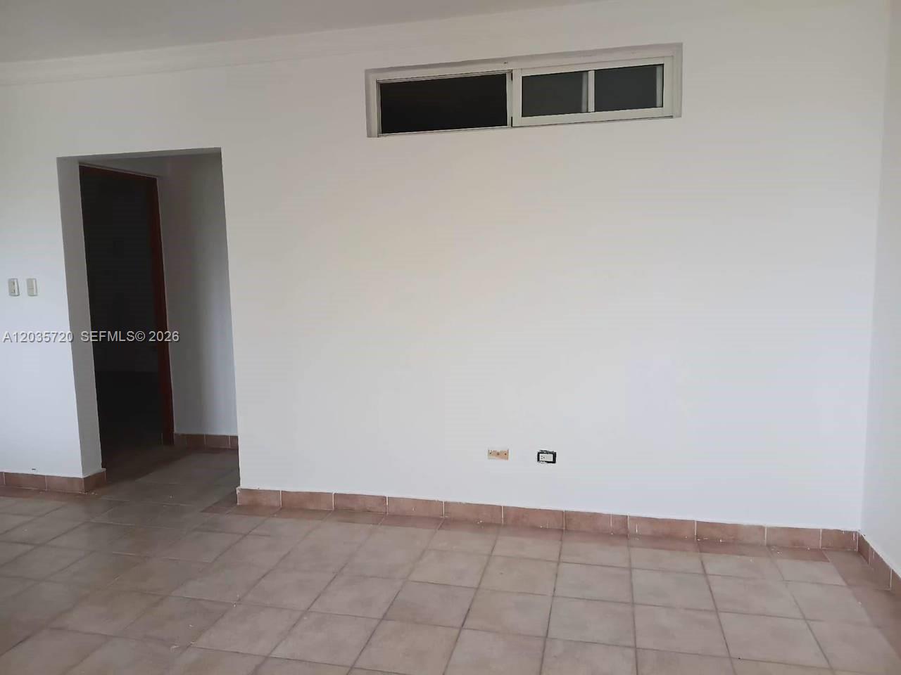 An empty room features white walls, a tiled floor, and a small rectangular window — 1 Punta cana # 1, FL