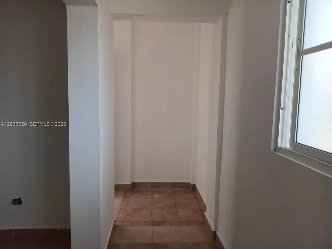 A small, empty alcove features light-colored walls and brown tiled flooring — 1 Punta cana # 1, FL