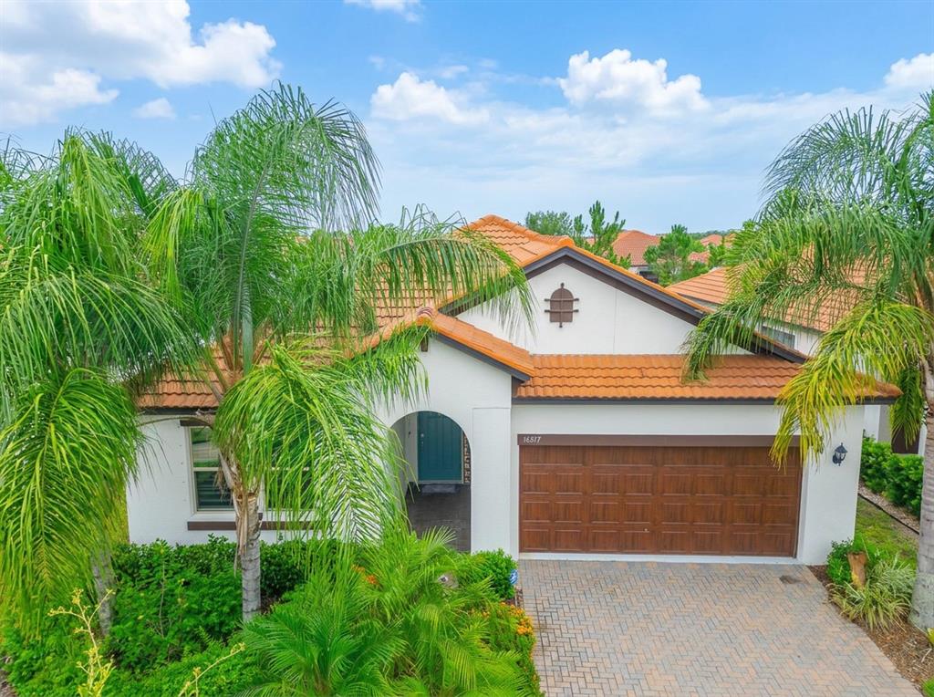 A single-story house with a terracotta tile roof, white stucco walls, and a wooden garage — 16817 WHISPER ELM STREET, WIMAUMA, FL