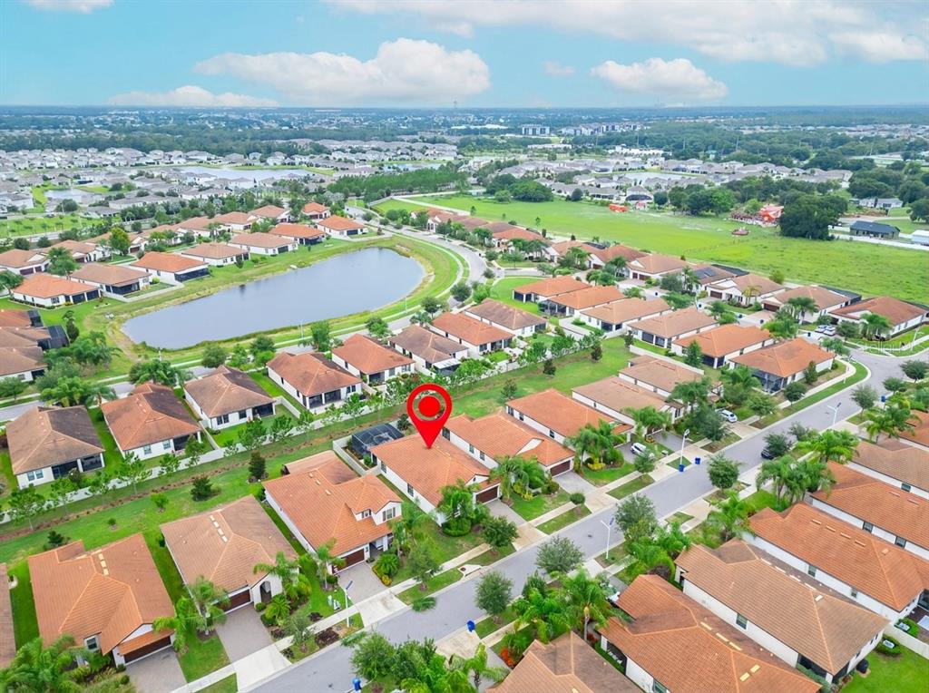 An aerial view of a suburban neighborhood featuring single-family homes with orange-tiled roofs — 16817 WHISPER ELM STREET, WIMAUMA, FL
