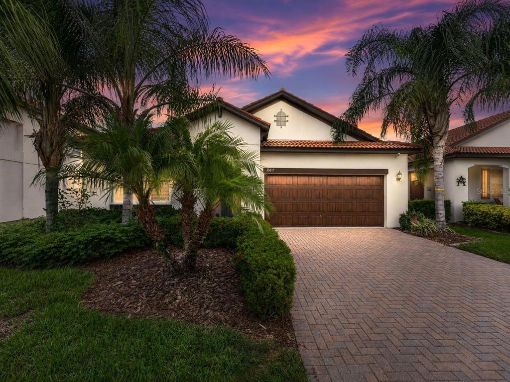A single-story house with a brown garage door, palm trees, and a brick paver driveway — 16817 WHISPER ELM STREET, WIMAUMA, FL