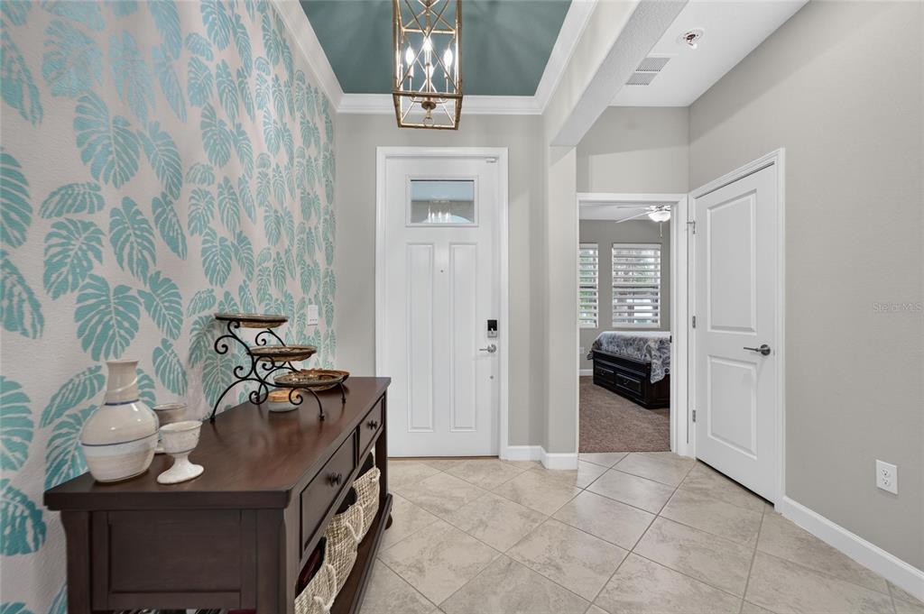 An entryway features a patterned accent wall, a dark wood console table, and tile flooring — 16817 WHISPER ELM STREET, WIMAUMA, FL