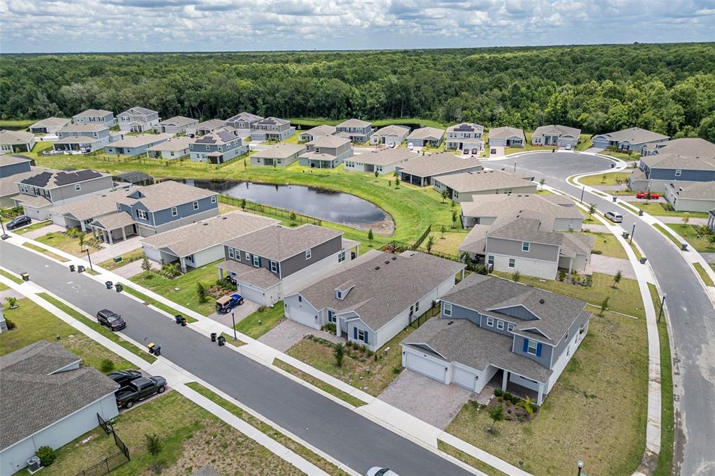 An aerial view shows a suburban neighborhood with houses surrounding a central retention pond — 4507 HILLINGDAM ROAD, DAVENPORT, FL