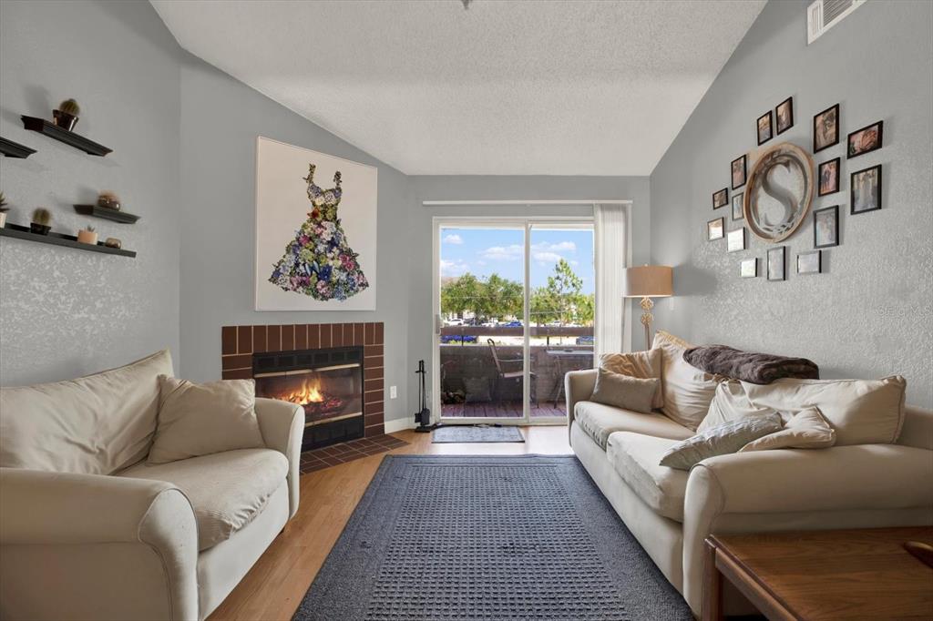 A living room features a fireplace, two sofas, a rug, and a sliding glass door — 10265 GANDY BOULEVARD N UNIT 906, ST PETERSBURG, FL