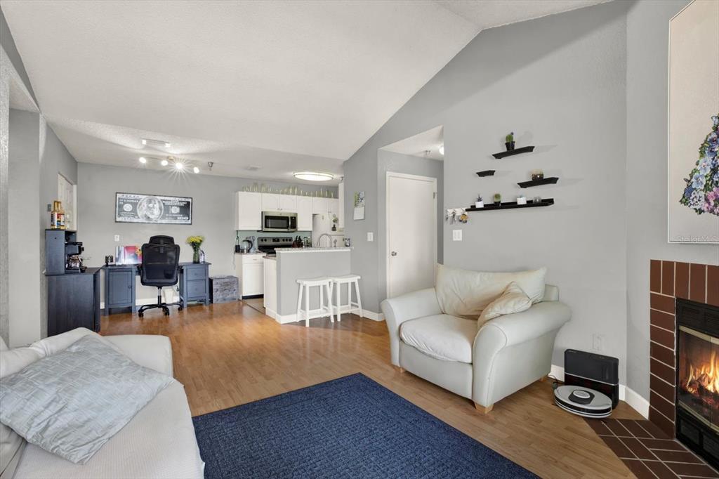 A living room with light wood floors, a fireplace, and an open kitchen in the background — 10265 GANDY BOULEVARD N UNIT 906, ST PETERSBURG, FL