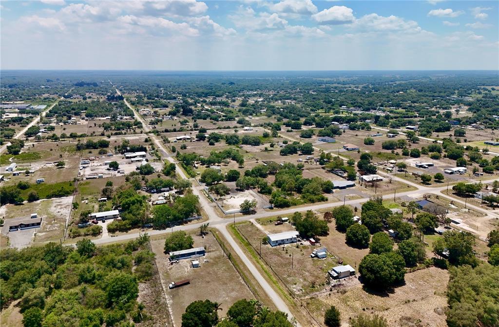 An aerial view shows a rural landscape with scattered houses, trees, and dirt roads — 242 BALD CYPRESS AVENUE, CLEWISTON, FL