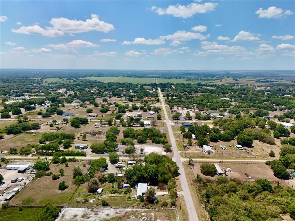 An aerial view shows a rural residential area with scattered houses and trees along a road — 242 BALD CYPRESS AVENUE, CLEWISTON, FL