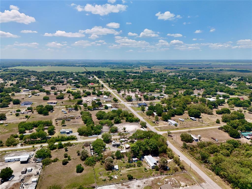 An aerial view shows a rural residential area with scattered houses, trees, and dirt roads — 242 BALD CYPRESS AVENUE, CLEWISTON, FL