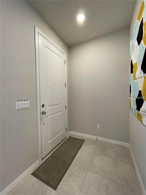 An entryway features a white door, light gray walls, tile flooring, and a patterned wall hanging — 5032 WALKER STREET, ST CLOUD, FL