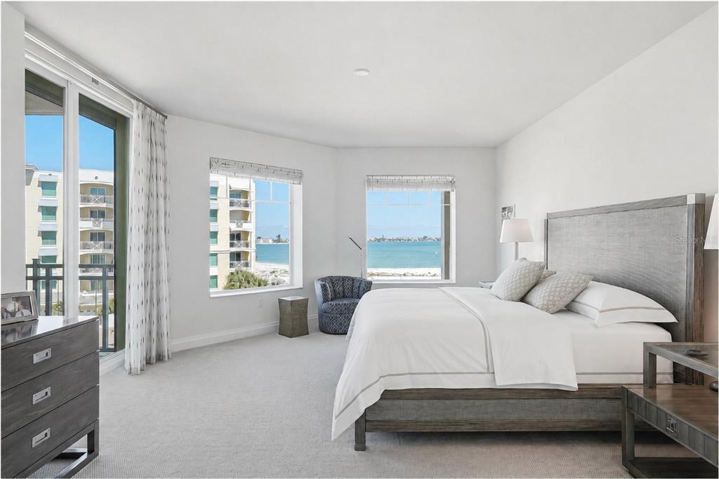 A bedroom with a king bed, gray furniture, carpeted floors, and views of the ocean — 650 COLLANY ROAD UNIT 401, TIERRA VERDE, FL