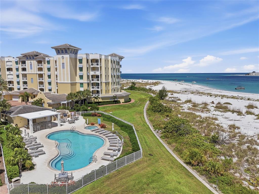 An aerial view shows a swimming pool, a multi-story building, and a sandy beach — 650 COLLANY ROAD UNIT 401, TIERRA VERDE, FL