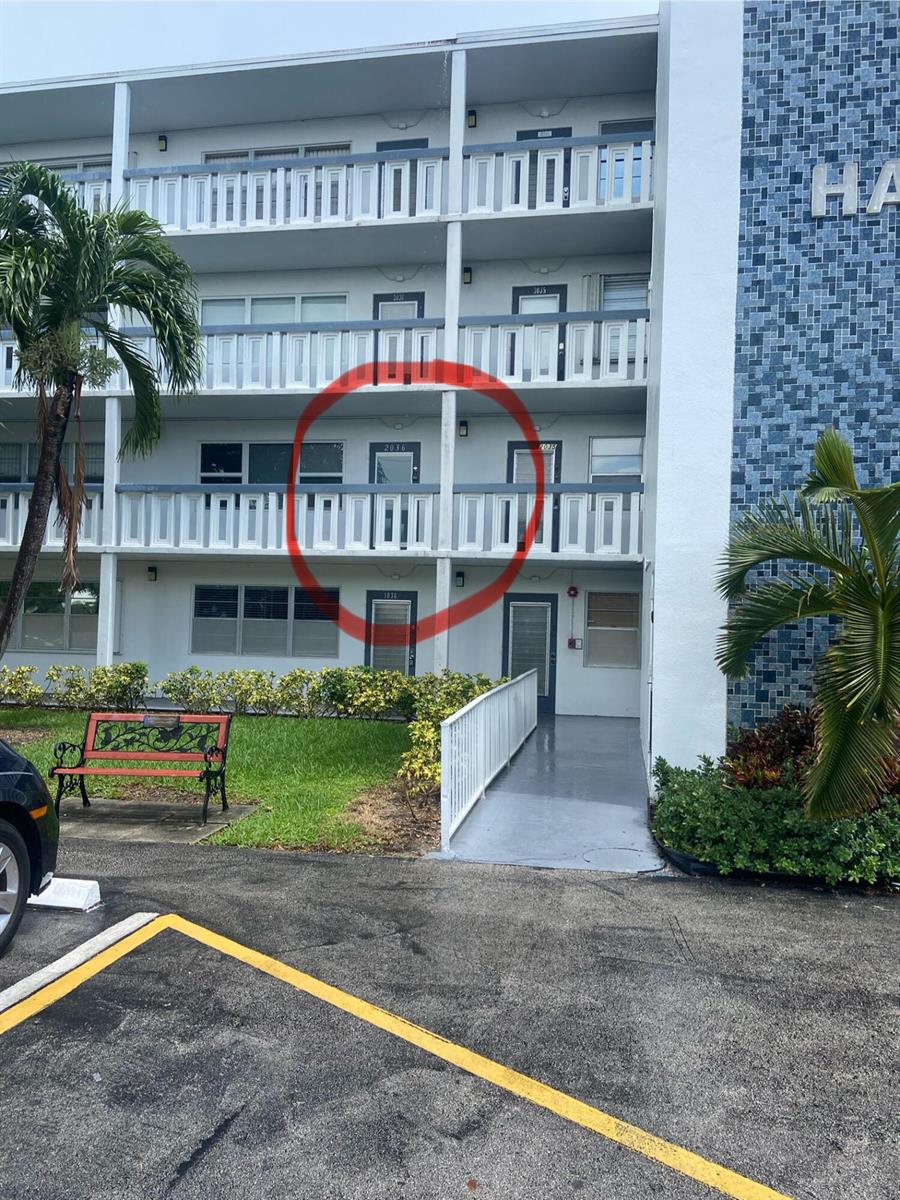 Exterior view of a multi-story apartment building with a red circle highlighting a unit door — 2036 Harwood D, Deerfield Beach FL 33442, DEERFIELD BEACH, FL