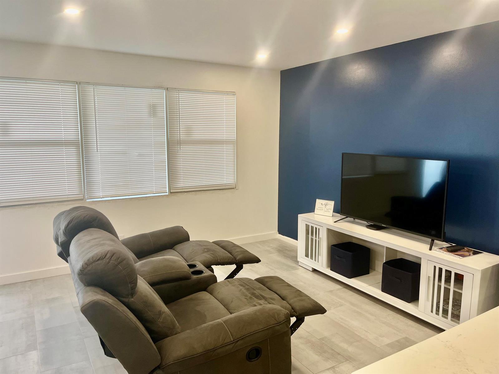 A living room features a dark blue accent wall, a television console, and reclining chairs — 2036 Harwood D, Deerfield Beach FL 33442, DEERFIELD BEACH, FL