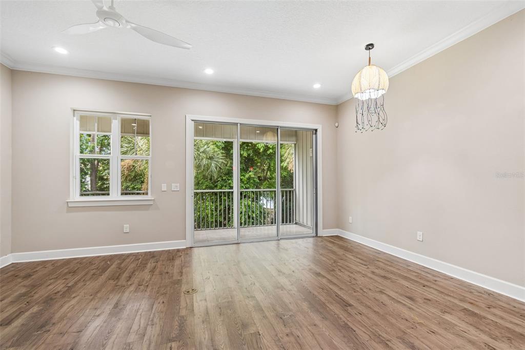 An empty room with wood-look flooring, a ceiling fan, a chandelier, and sliding glass doors — 3144 NAUTICAL PLACE S, ST PETERSBURG, FL