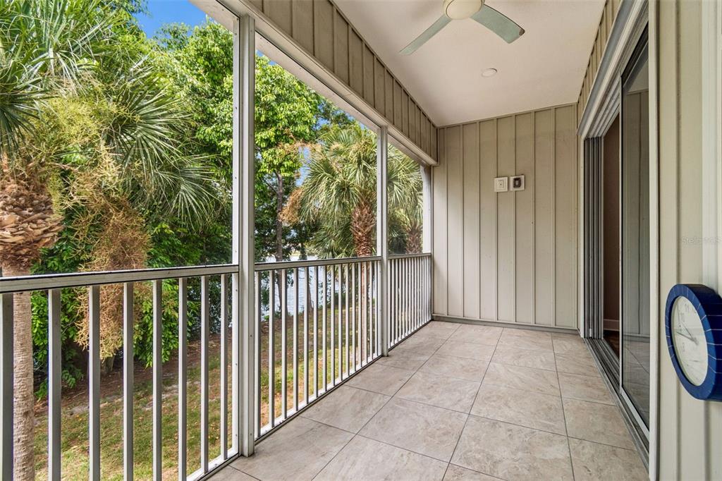 A screened-in balcony with tiled flooring, a ceiling fan, and a view of trees — 3144 NAUTICAL PLACE S, ST PETERSBURG, FL