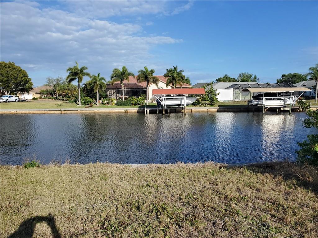 A canal view shows two boat lifts with covered boats in front of a residential home — 4228 EASTLAKE COURT, PORT CHARLOTTE, FL