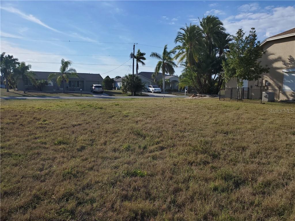 A vacant, grassy lot sits in front of several single-story houses and palm trees — 4228 EASTLAKE COURT, PORT CHARLOTTE, FL