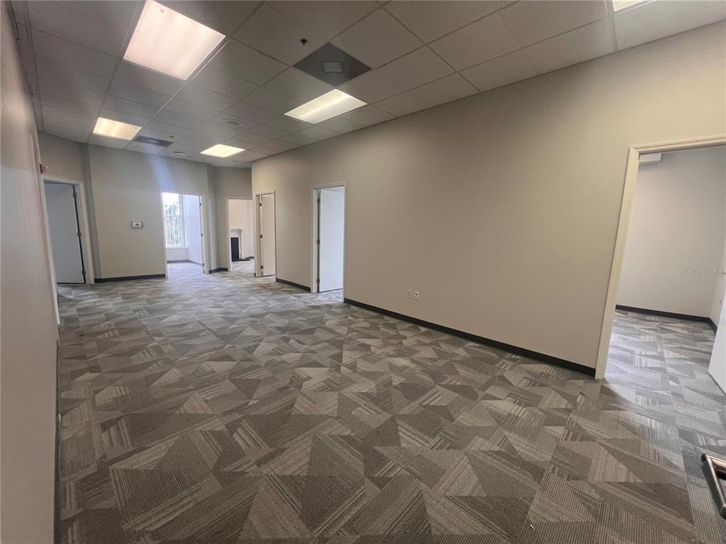 An empty office space features gray patterned carpeting, white walls, and a drop ceiling — 110 W 1ST STREEET UNIT 210, SANFORD, FL