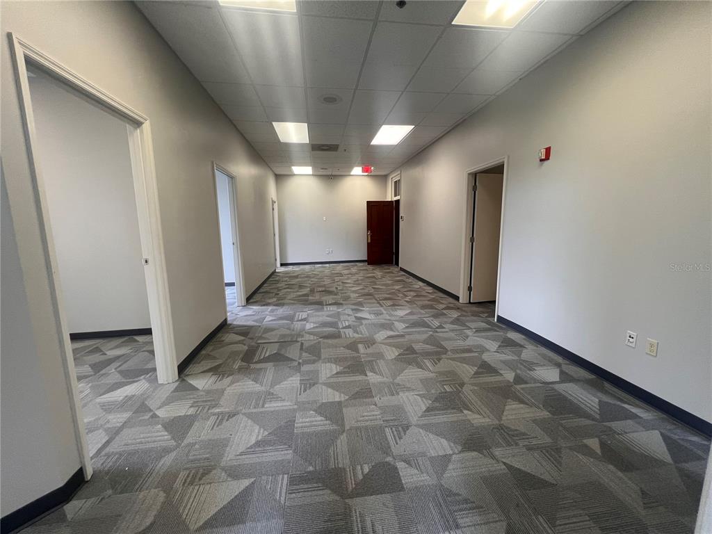 An empty office hallway features gray patterned carpet, white walls, and a drop ceiling — 110 W 1ST STREEET UNIT 210, SANFORD, FL